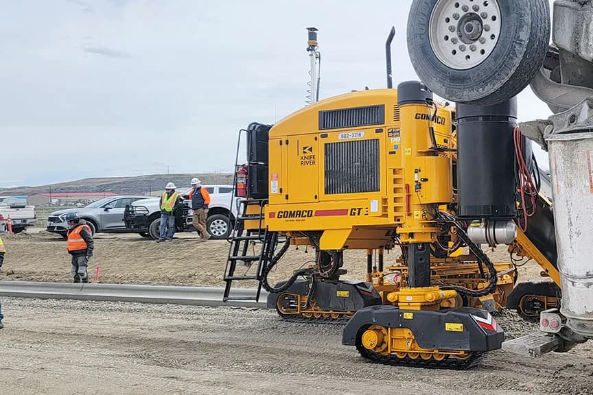 GOMACO GT-3600 side view beside a concrete truck on a curb project